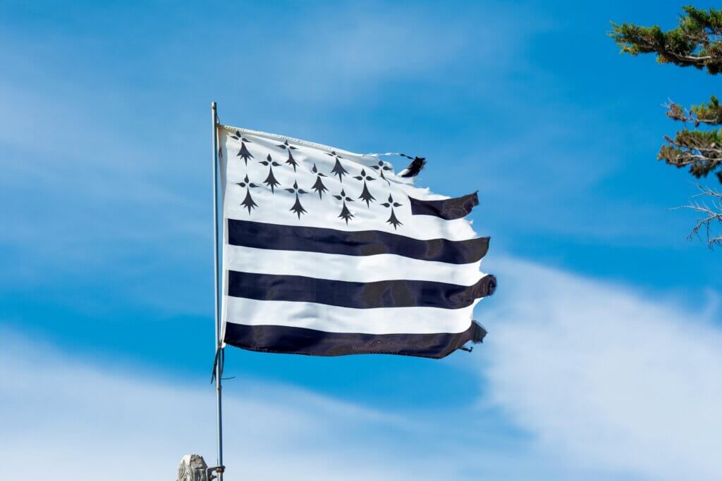 Drapeau breton Gwenn-ha-du flottant au vent sous un ciel bleu